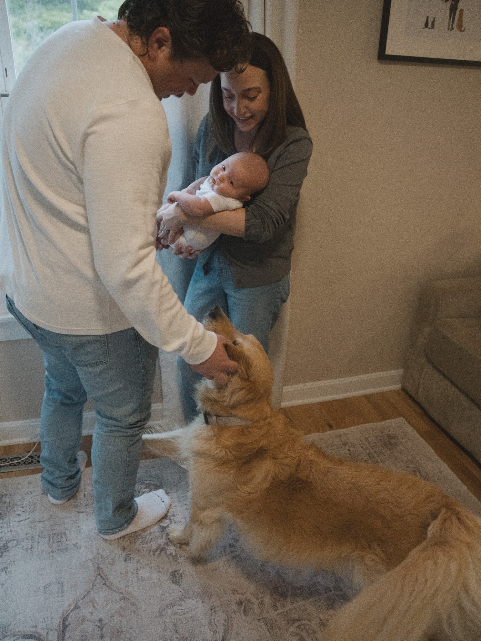 Parents holding their baby at home beside their dog